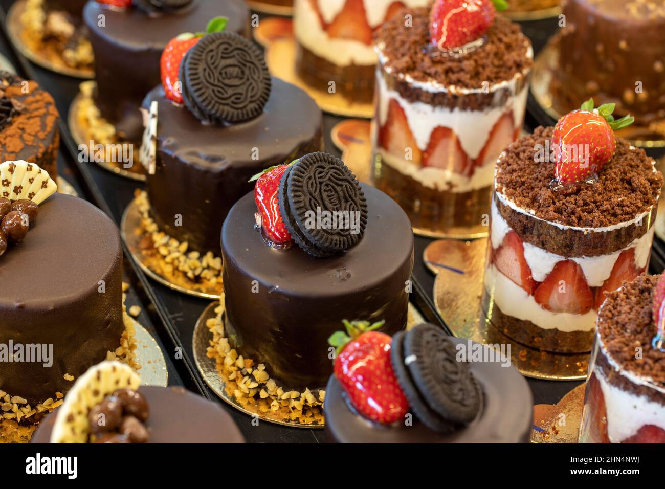 Pequeños pasteles en la pantalla en el mostrador de la pastelería Foto de stock