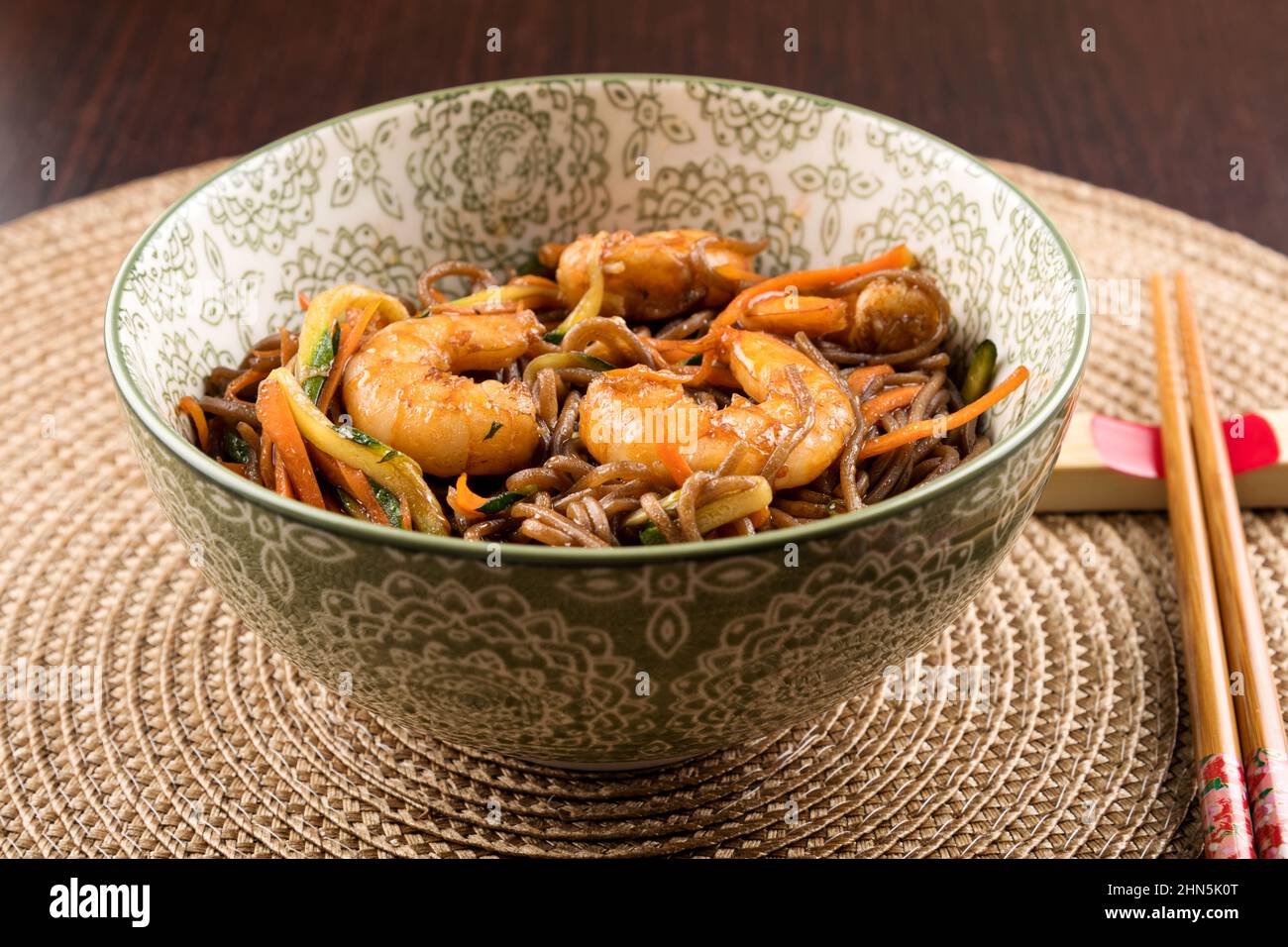 Desde la parte superior del tazón con sabrosos fideos yakisoba con gambas colocadas cerca de palillos en la mesa Foto de stock