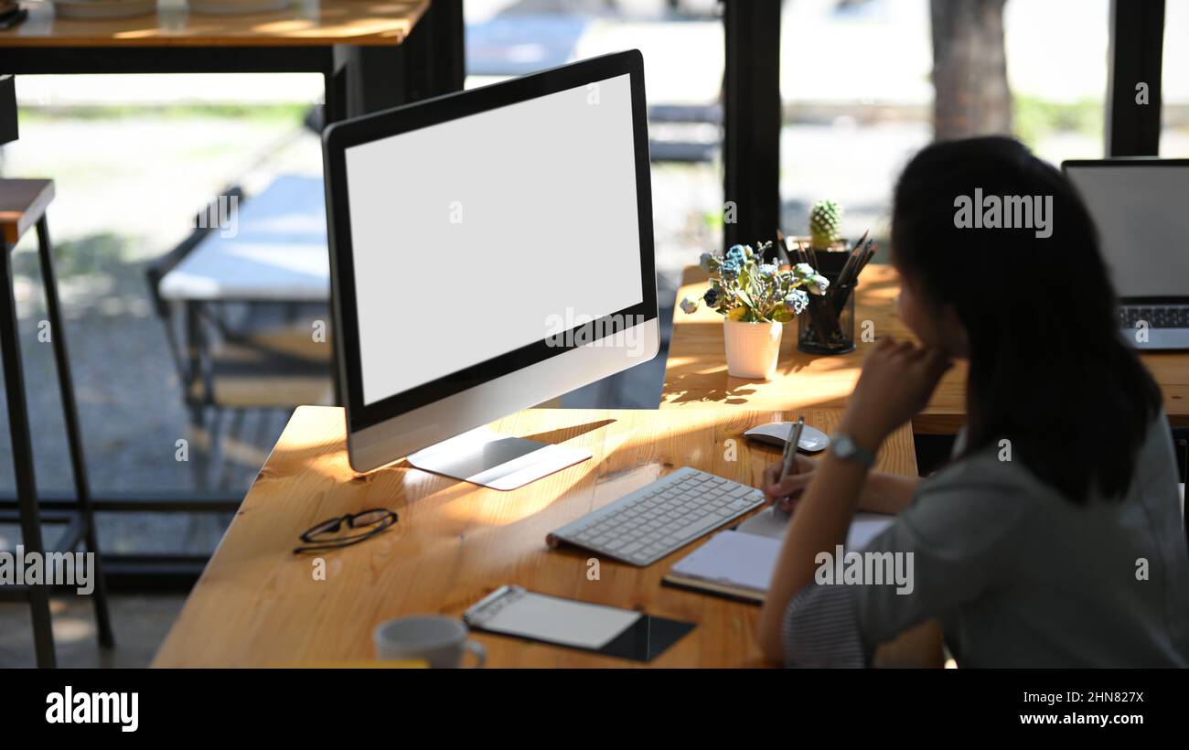 Una asistente o secretaria mujer trabajando en su ordenador de escritorio  de pc en su escritorio. Computadora pantalla blanca mockup Fotografía de  stock - Alamy