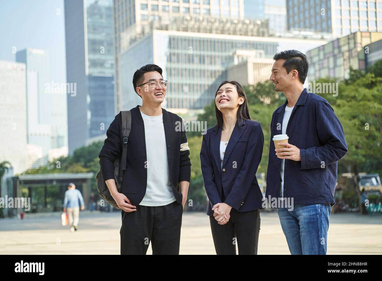 jóvenes asiáticos de pie hablando en la calle feliz y sonriente Foto de stock