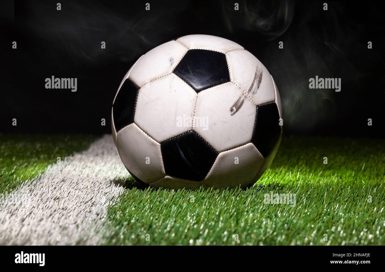 Vista en ángulo bajo de la pelota de fútbol en campo de hierba con fondo oscuro y humo Foto de stock