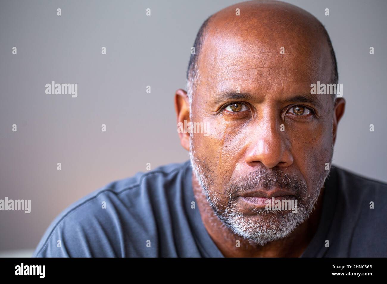 Retrato de un hombre maduro que se ve triste con lágrimas en sus ojos. Foto de stock