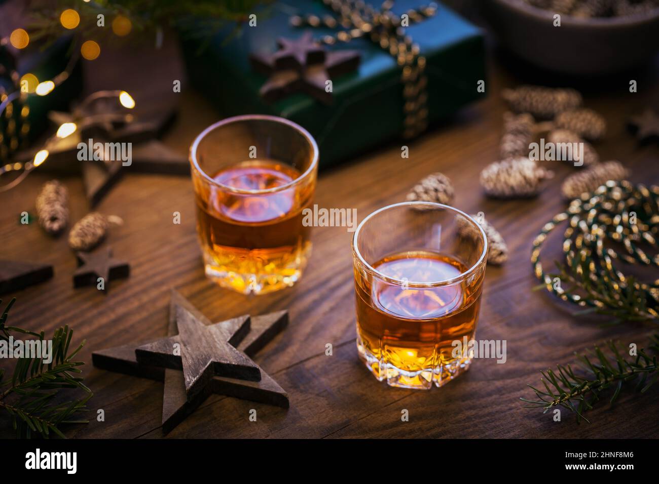Dos copas de whisky o bourbon con decoración de vacaciones sobre fondo de madera. Año Nuevo, Navidad y vacaciones de invierno concepto de humor whisky Foto de stock