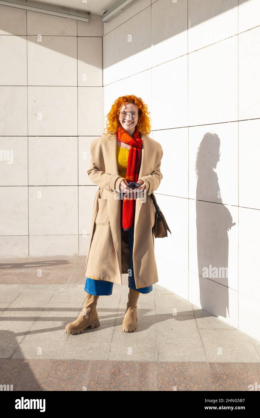 Mujer de jengibre vestida con ropa moderna y casual sonriendo Foto de stock