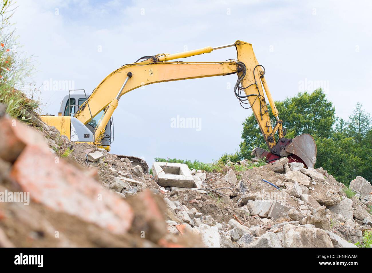 Una excavadora moderna limpia los escombros de un edificio después de un terremoto Foto de stock