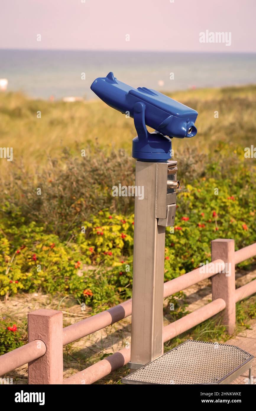Un par de prismáticos, telescopio se encuentra sobre una playa para observar el mar. Foto de stock