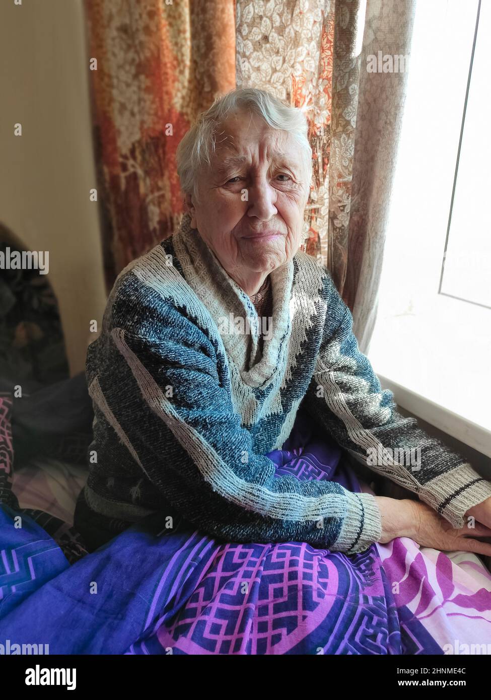 La mujer de más edad con gas bill delante del radiador de calefacción. El pago de la calefacción en invierno. Foto de stock