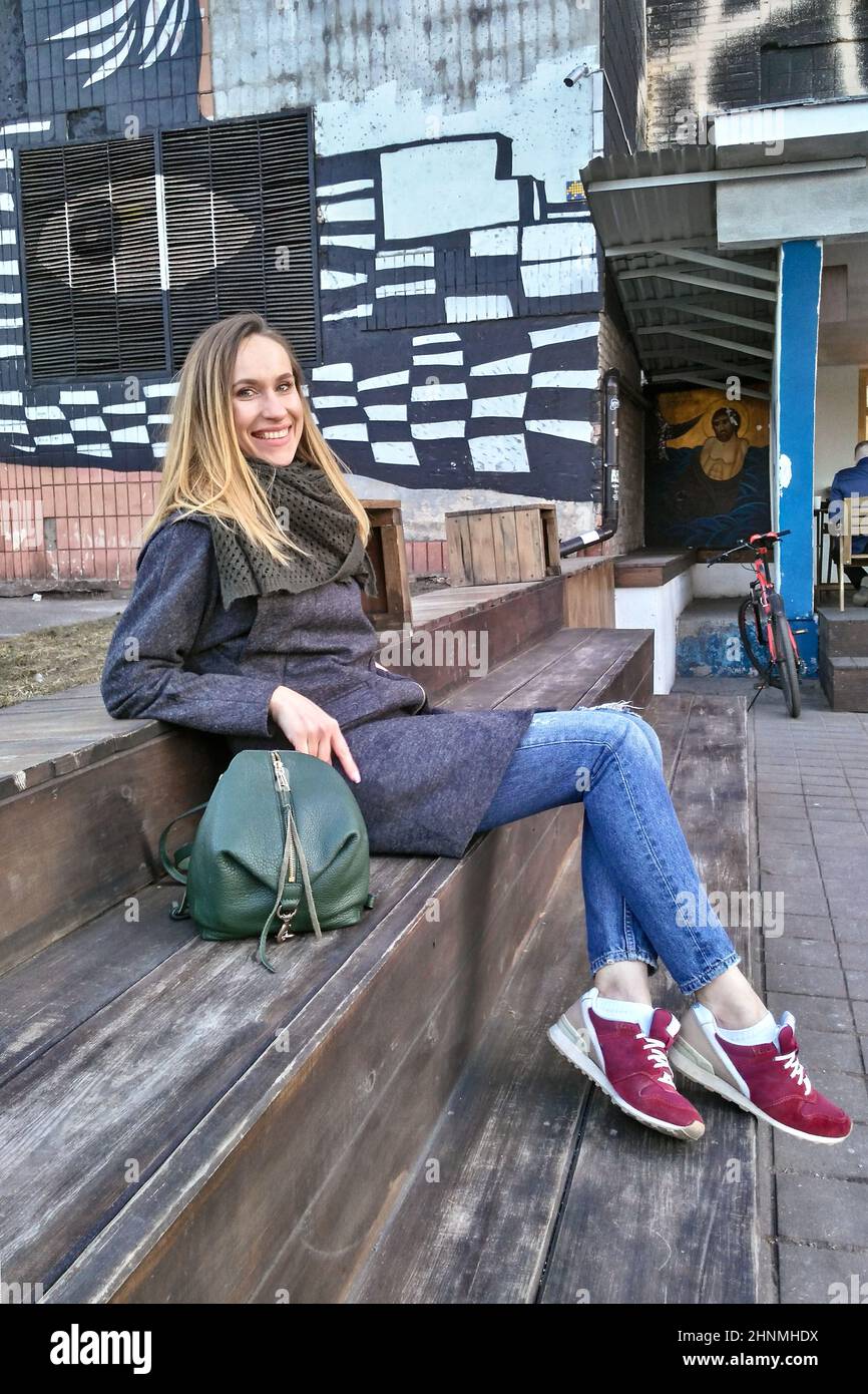 Mujer afortunada con abrigo, jeans y zapatillas de deporte en el casco  antiguo Fotografía de stock - Alamy