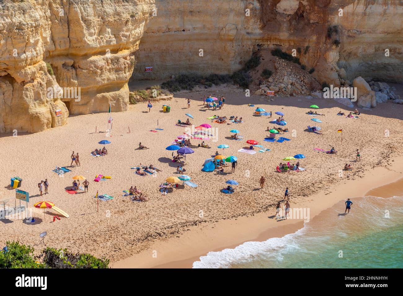 La gente disfruta de la pintoresca playa en la costa del Algarve cerca de Carvoeiro y sigue las reglas para los turistas en la playa según las reglas de Corona Foto de stock