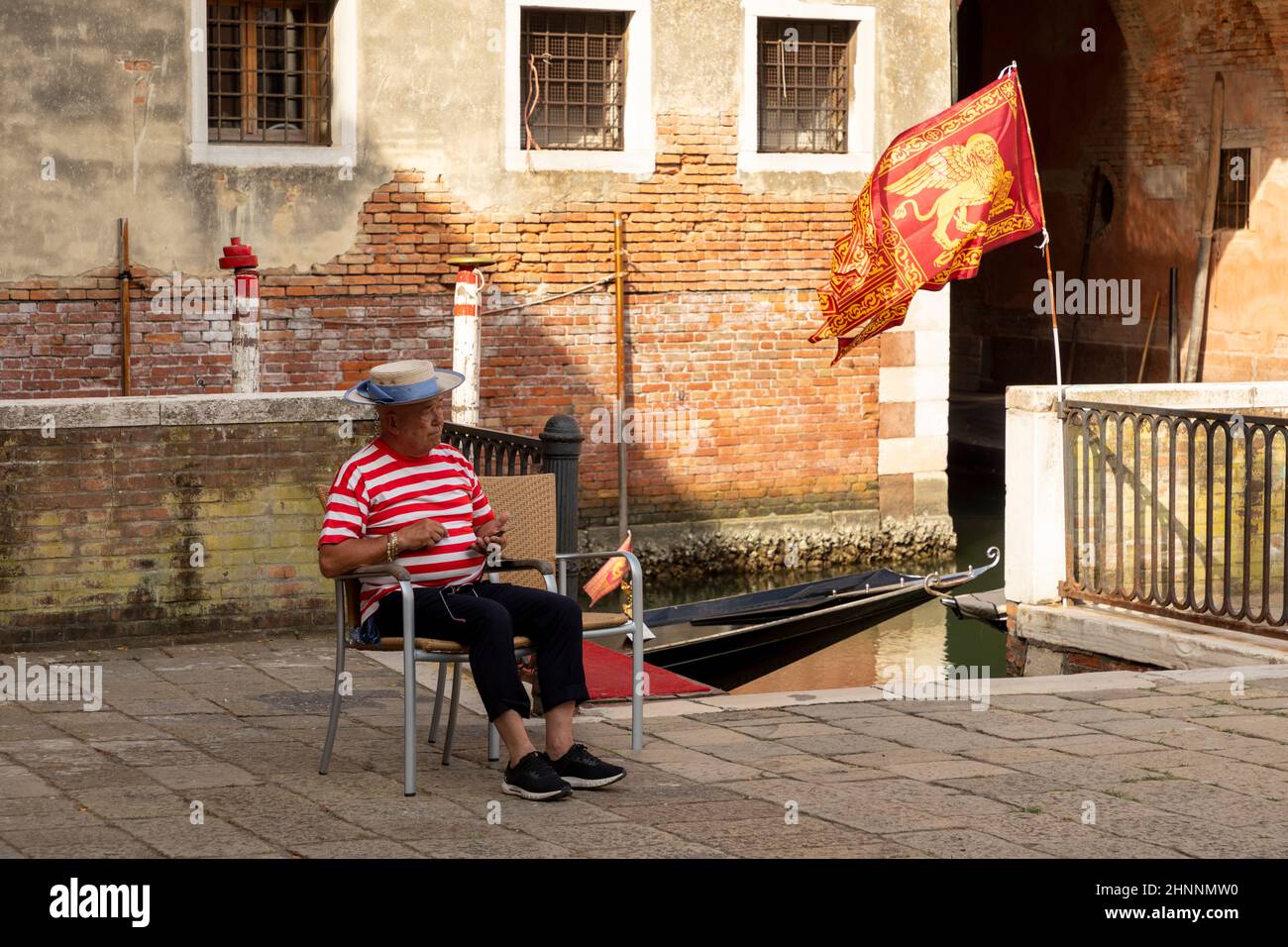 gondolier se sienta en una silla y espera a los turistas. Debido a la pandemia de Corona, sólo hay unos pocos turistas en Venecia, Italia Foto de stock