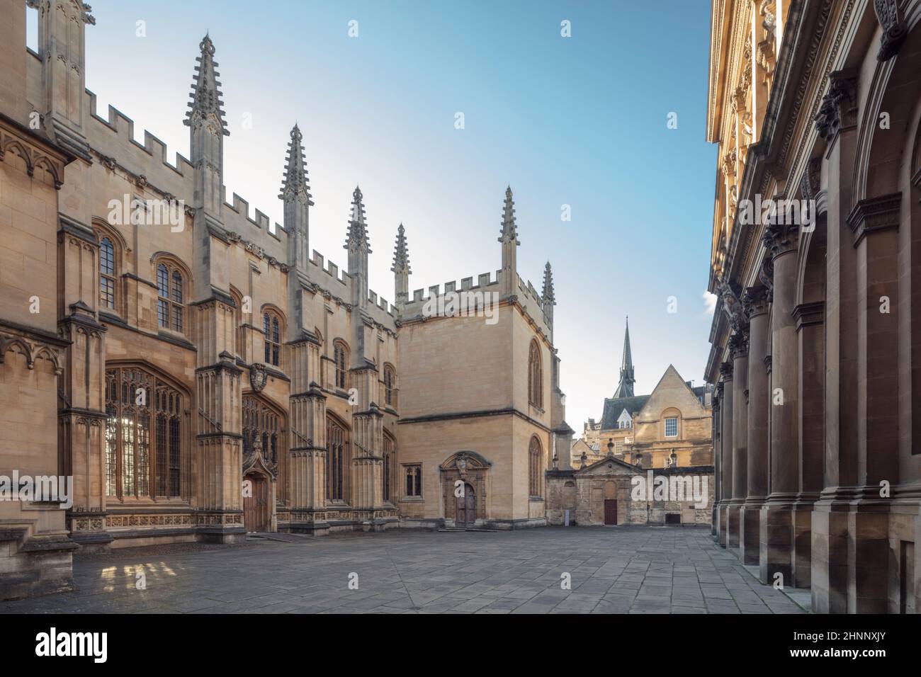 Reino Unido, Universidad de Oxford. Fachada norte de la Escuela de Divinidad gótica medieval con el Teatro Sheldoniano (primer plano, a la derecha), sin gente, día soleado. Foto de stock