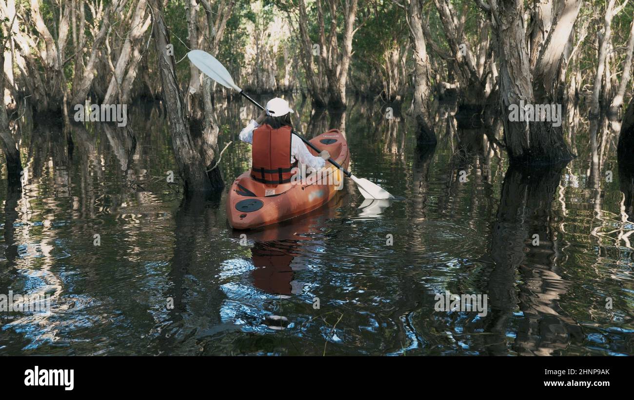 Espalda joven mujer adulta remando canoa kayak en un lago el día de verano Foto de stock