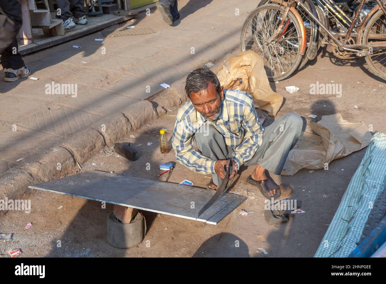 Hombre con sierra corta una placa rigips en la calle en la vieja Delhi, Chawri Bazaar. Foto de stock