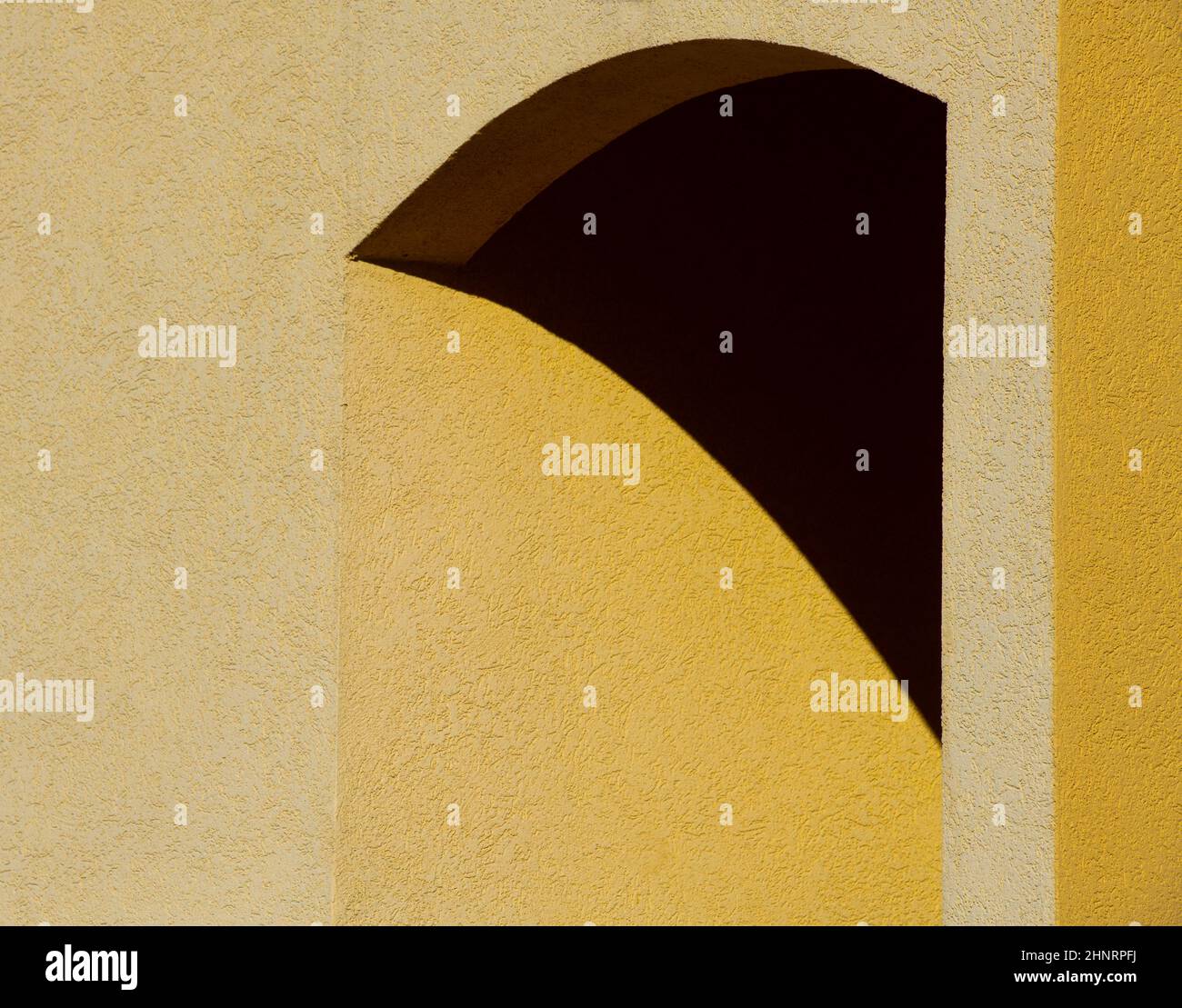 diseño abstracto sombra sobre hormigón amarillo pared de cemento de formas geométricas arco de construcción exterior líneas curvas triangulares y ángulos de contraste Foto de stock