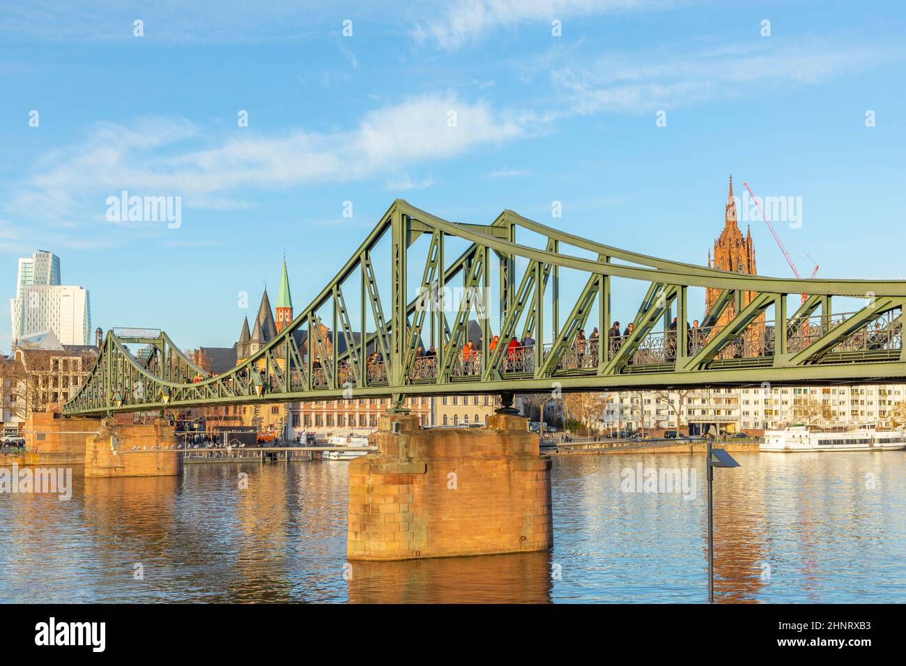 Puente peatonal que cruza el río Main llamado puente de hierro (eiserner Steg) en Frankfurt, Alemania con el horizonte Foto de stock