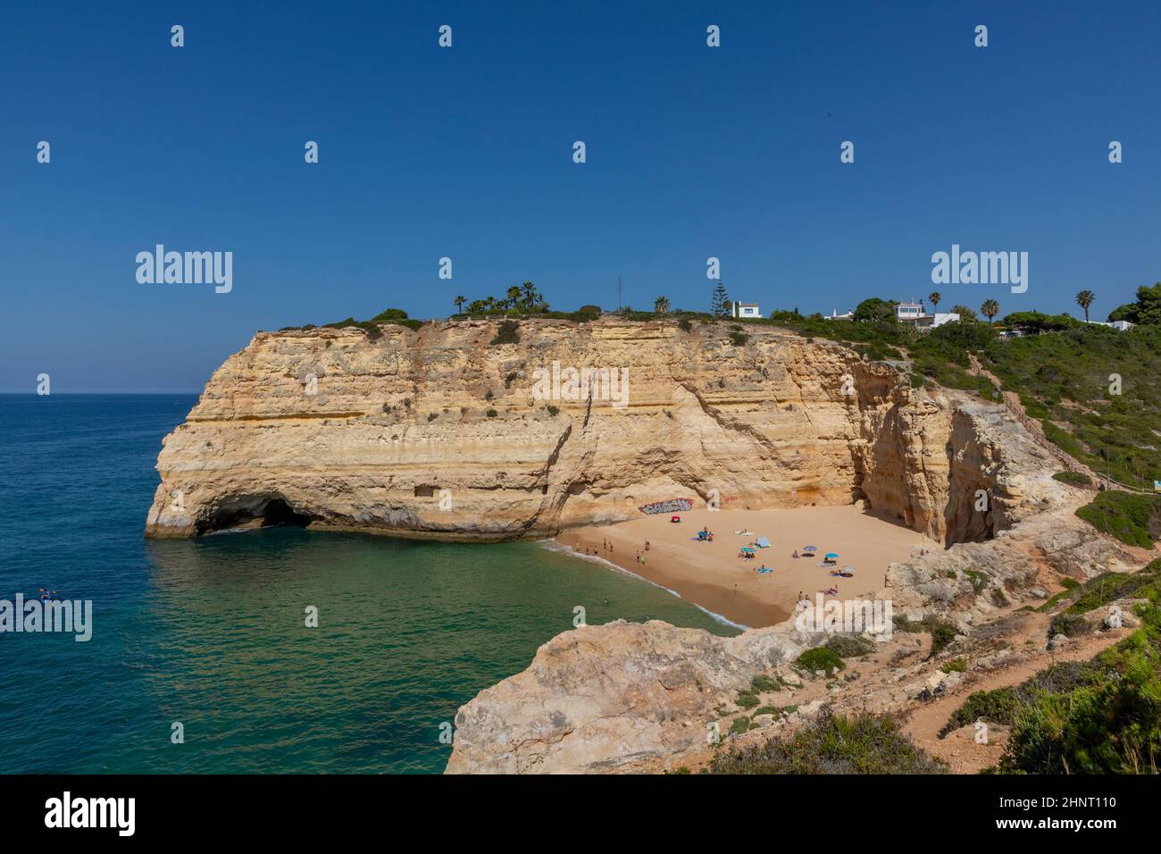 La gente disfruta de la pintoresca playa en la costa del Algarve cerca de Carvoeiro y sigue las reglas para los turistas en la playa según las reglas de Corona Foto de stock