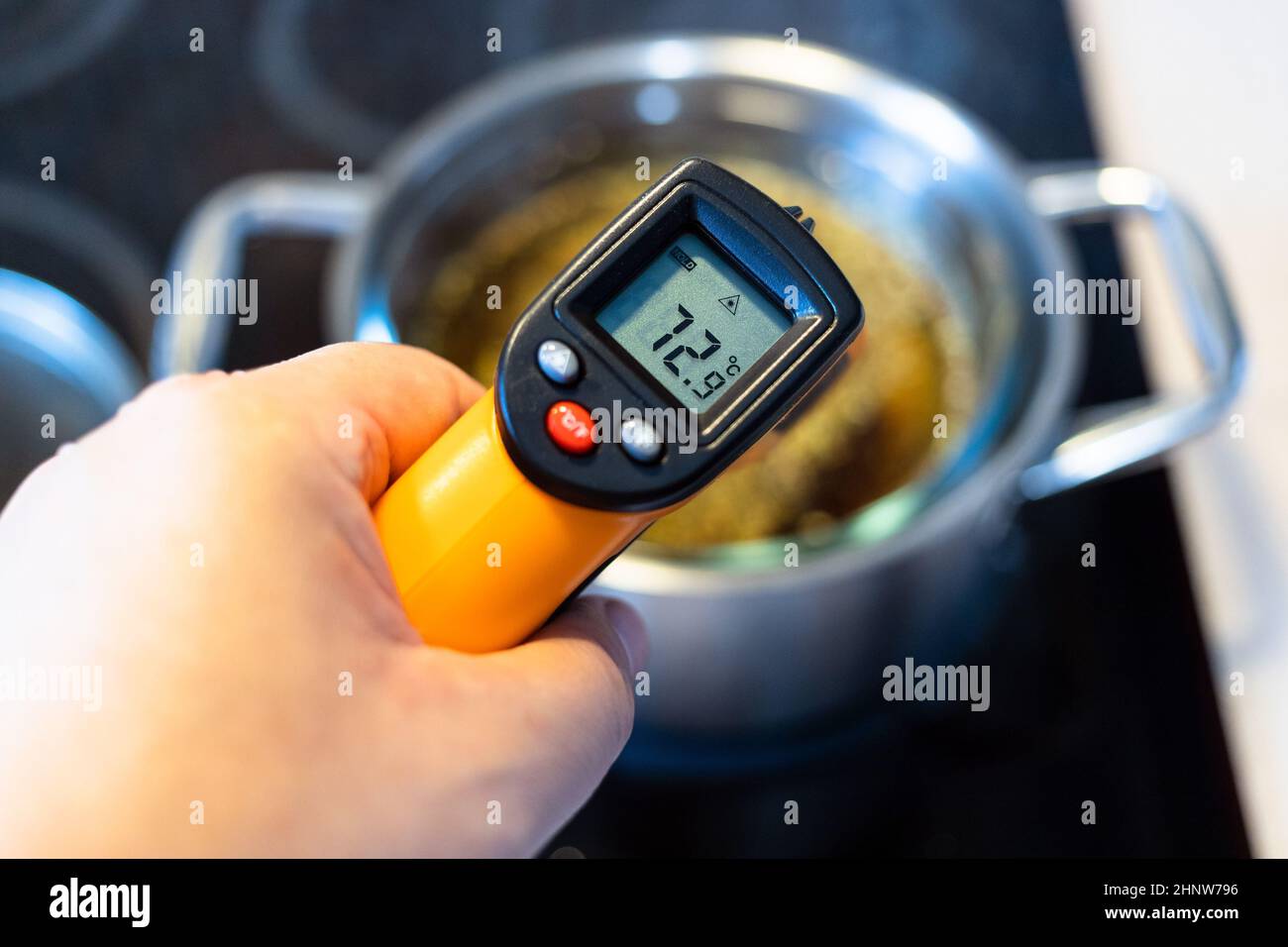 medición de la temperatura en el baño de agua mediante termómetro de  infrarrojos en estufa de cerámica en la cocina de casa Fotografía de stock  - Alamy