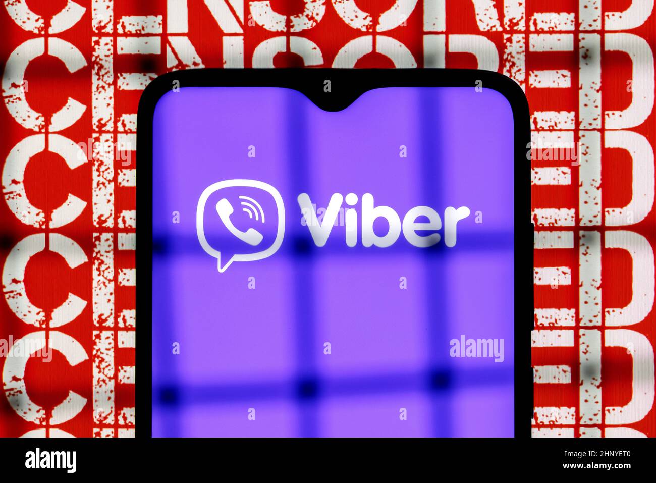 Viber servicio de mensajería instantánea logotipo en la pantalla del smartphone detrás de las barras en el fondo con inscripción censurada Foto de stock