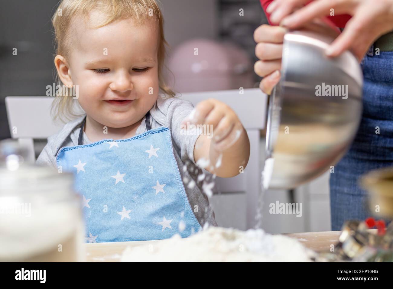 Pequeño ayudante. Lindo niño está jugando con harina rociada en la cocina. Foto de stock