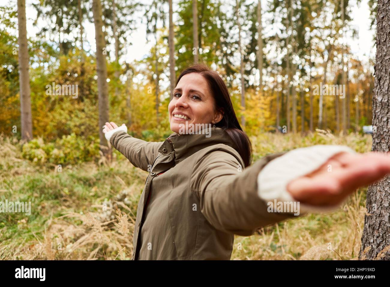 Mujer en el bosque haciendo un ejercicio de respiración para la relajación y el bienestar con sus brazos extendidos Foto de stock