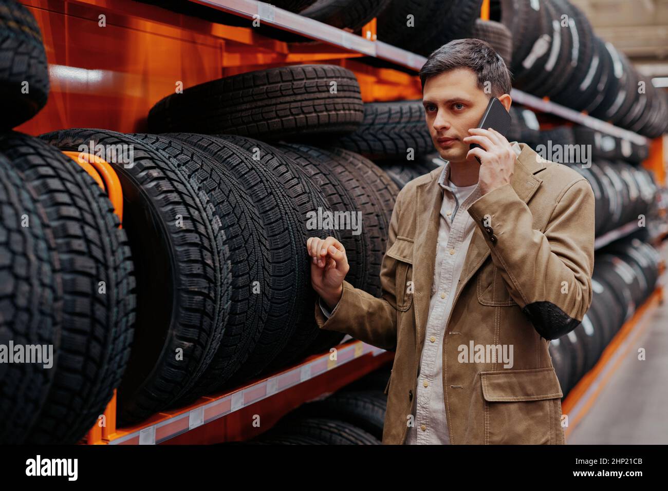 hombre cliente elegir neumáticos nuevos y hablar por teléfono en la tienda  de automóviles con artículos de automóviles Fotografía de stock - Alamy