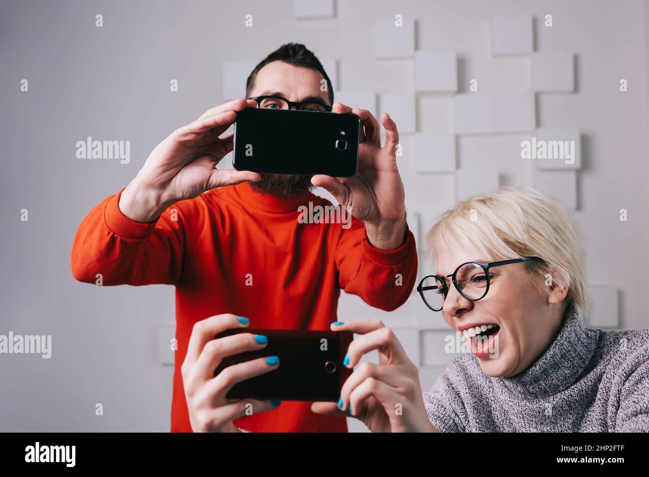 Pareja riendo divertirse con smartphones en un apartamento moderno Foto de stock