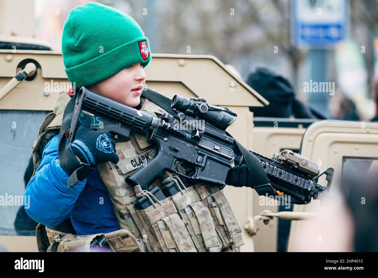 Niño o niño con chaleco militar de los Marines jugando la guerra con un arma cerca de un tanque o vehículo militar Foto de stock