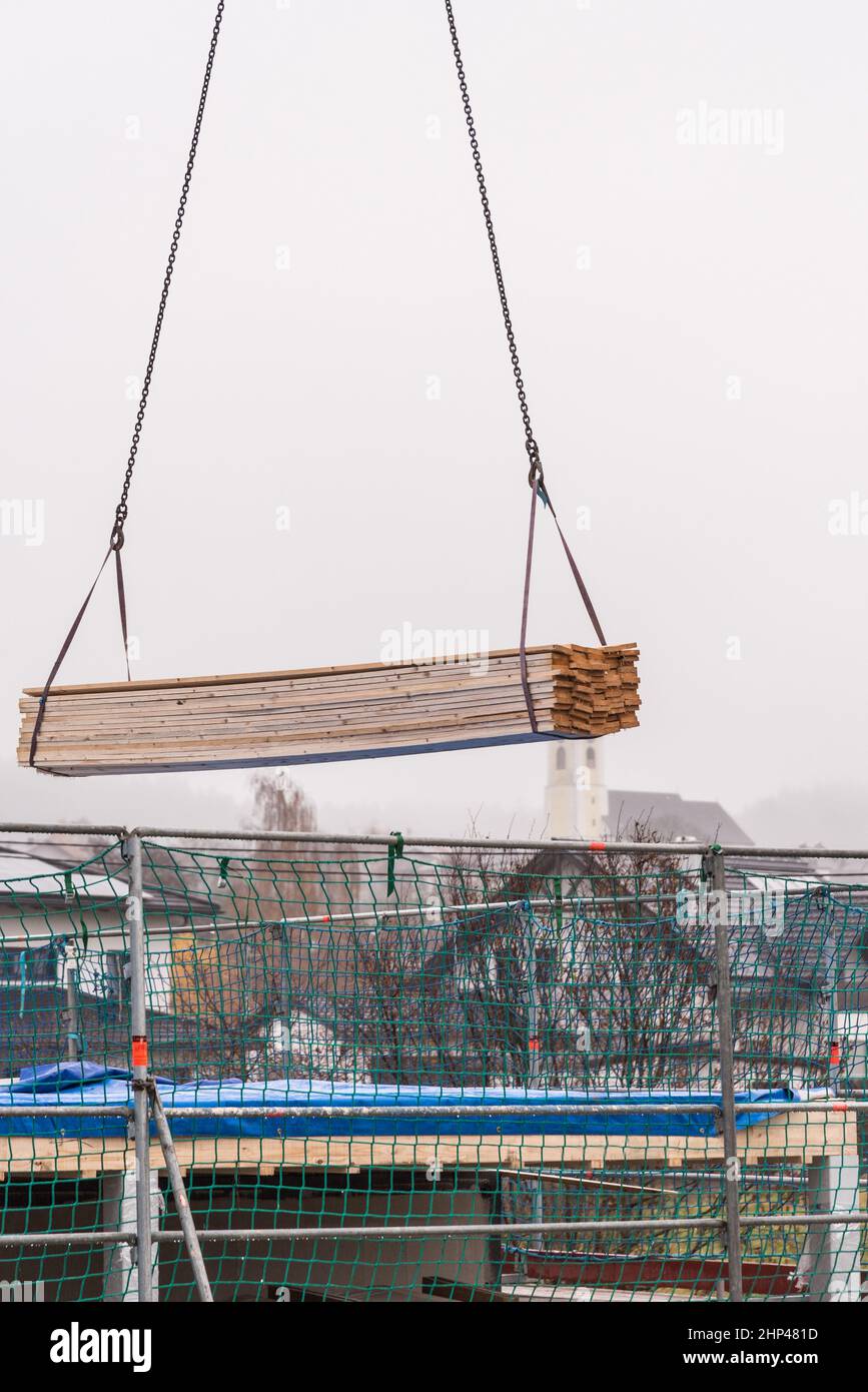 Nueva construcción de una casa - obra de construcción con entrega de madera por grúa Foto de stock