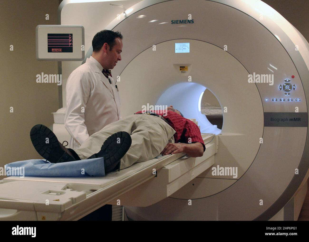 El tecnólogo de Radiología y Ciencias de la Imagen Rob Evers (izquierda) habla con un paciente antes de realizar una exploración en el dispositivo PET/RM simultáneo de cuerpo entero completamente integrado. 2011 Foto de stock