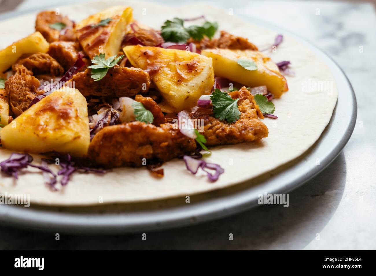 Burritos con rizos de TVP picantes, cornezos de col y piña fresca Foto de stock