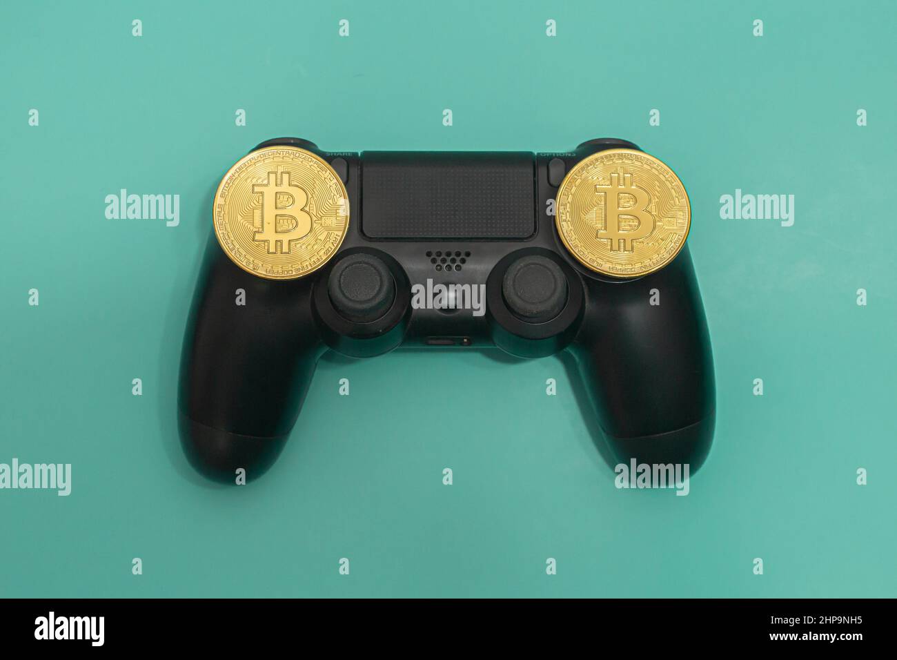 Mando para juegos negro con fichas Bitcoin aisladas sobre fondo verde. Foto de stock