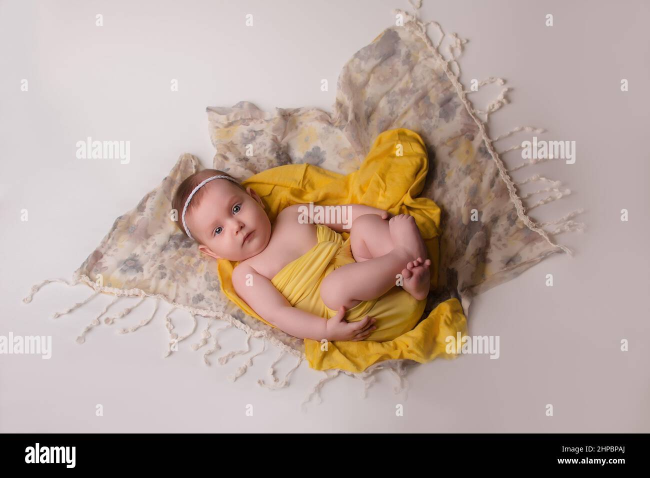un bebé recién nacido con ropa amarilla, fondo gris, está sobre su espalda.  Feliz infancia, con estilo para recién nacidos y niños Fotografía de stock  - Alamy