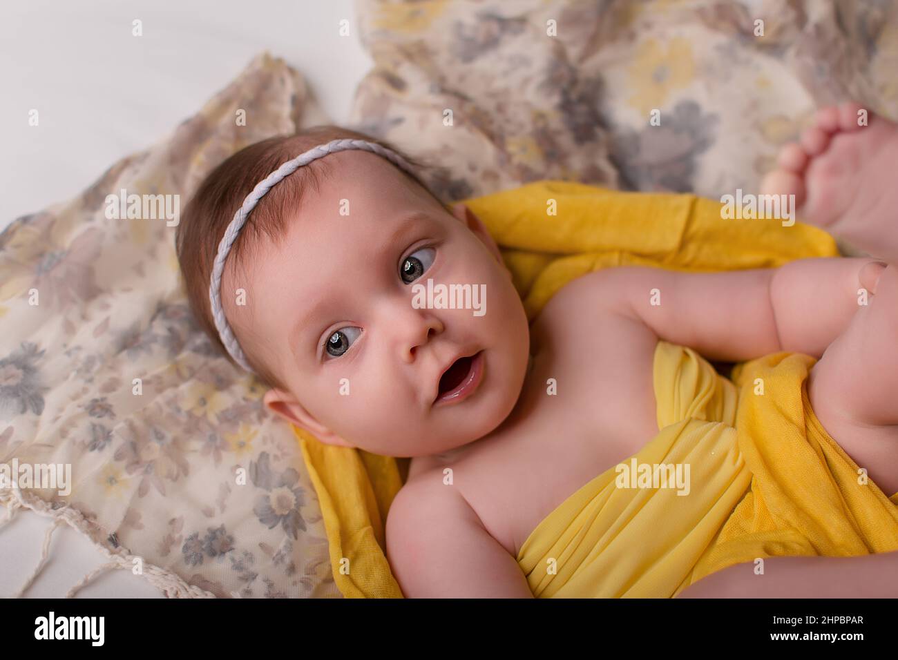 un bebé recién nacido con ropa amarilla, fondo gris, está sobre su espalda.  Feliz infancia, con estilo para recién nacidos y niños Fotografía de stock  - Alamy