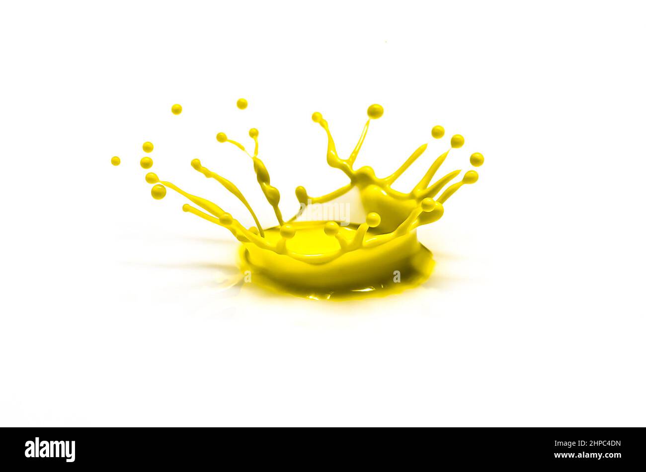 La gota de agua de color amarillo que golpea un plato blanco da forma a una corona. Foto como decoración de pared Foto de stock