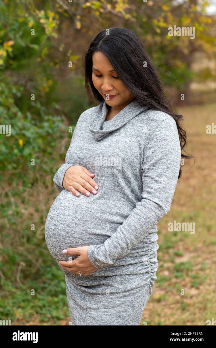 Mujer embarazada asiática feliz sosteniendo su estómago Foto de stock