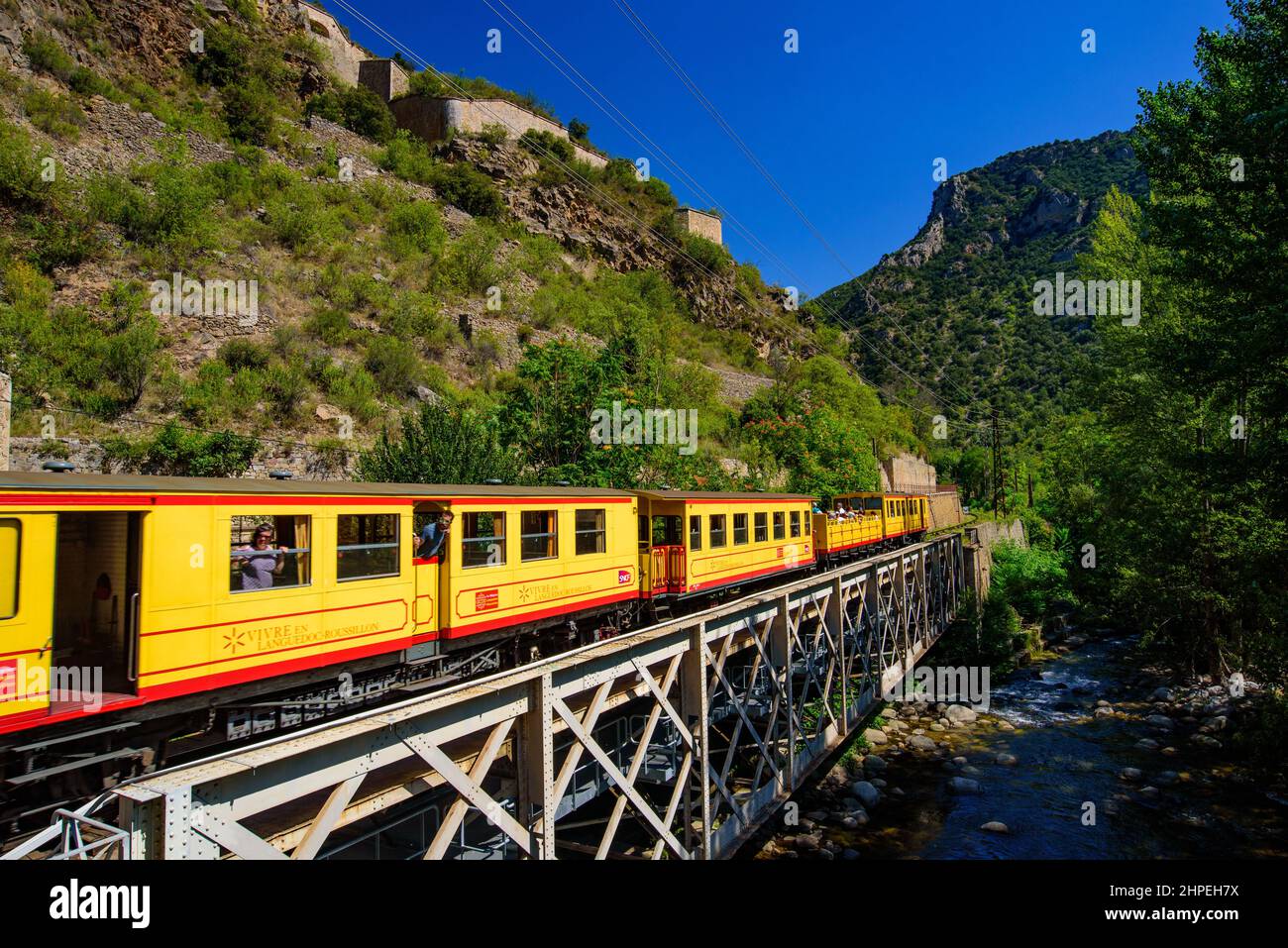 El Pequeño Tren Amarillo (Le Petit Train Jaune) pasando por Villefranche-de-Conflent, Francia Foto de stock