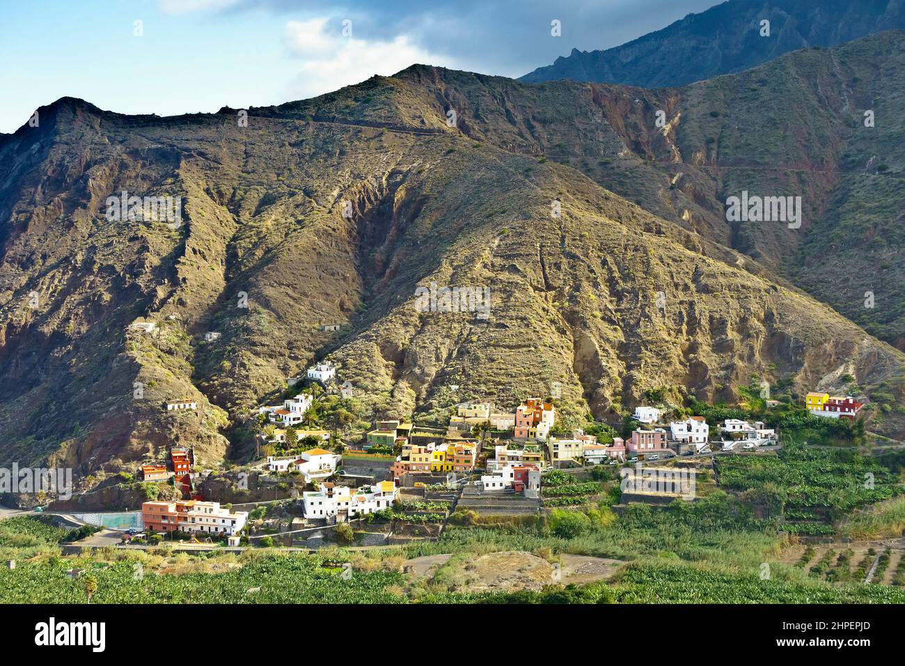 Hermigua pueblo, La Gomera, Islas Canarias: Coloridas casas en una ladera de montaña y plátanos en el valle, en invierno. Foto de stock