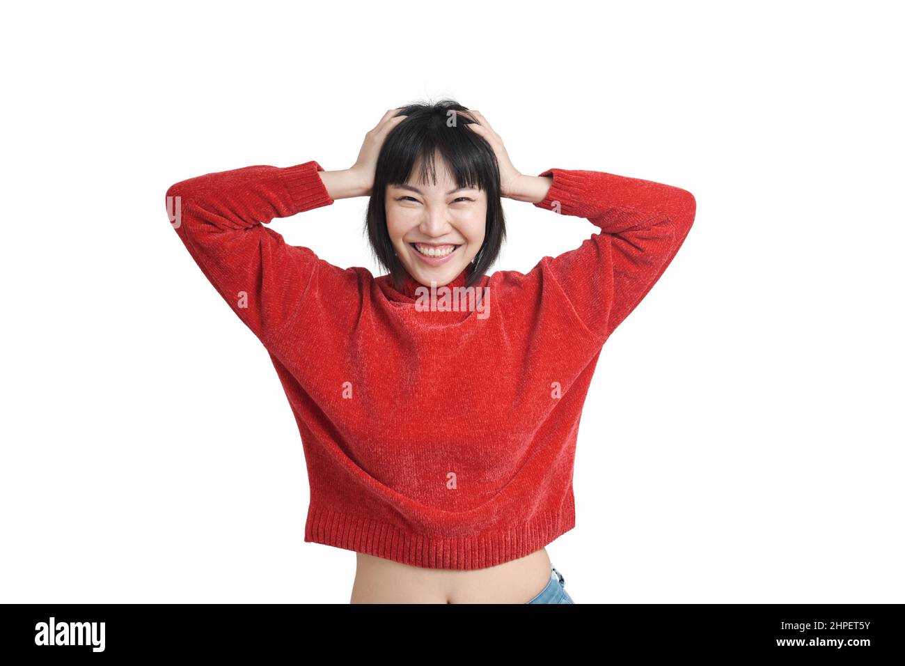 Joven mujer asiática riendo y tocando su cabeza con sus manos, aislada. Foto de stock