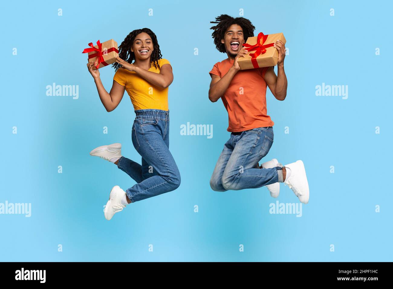 Feliz joven pareja negra con regalos saltando Foto de stock