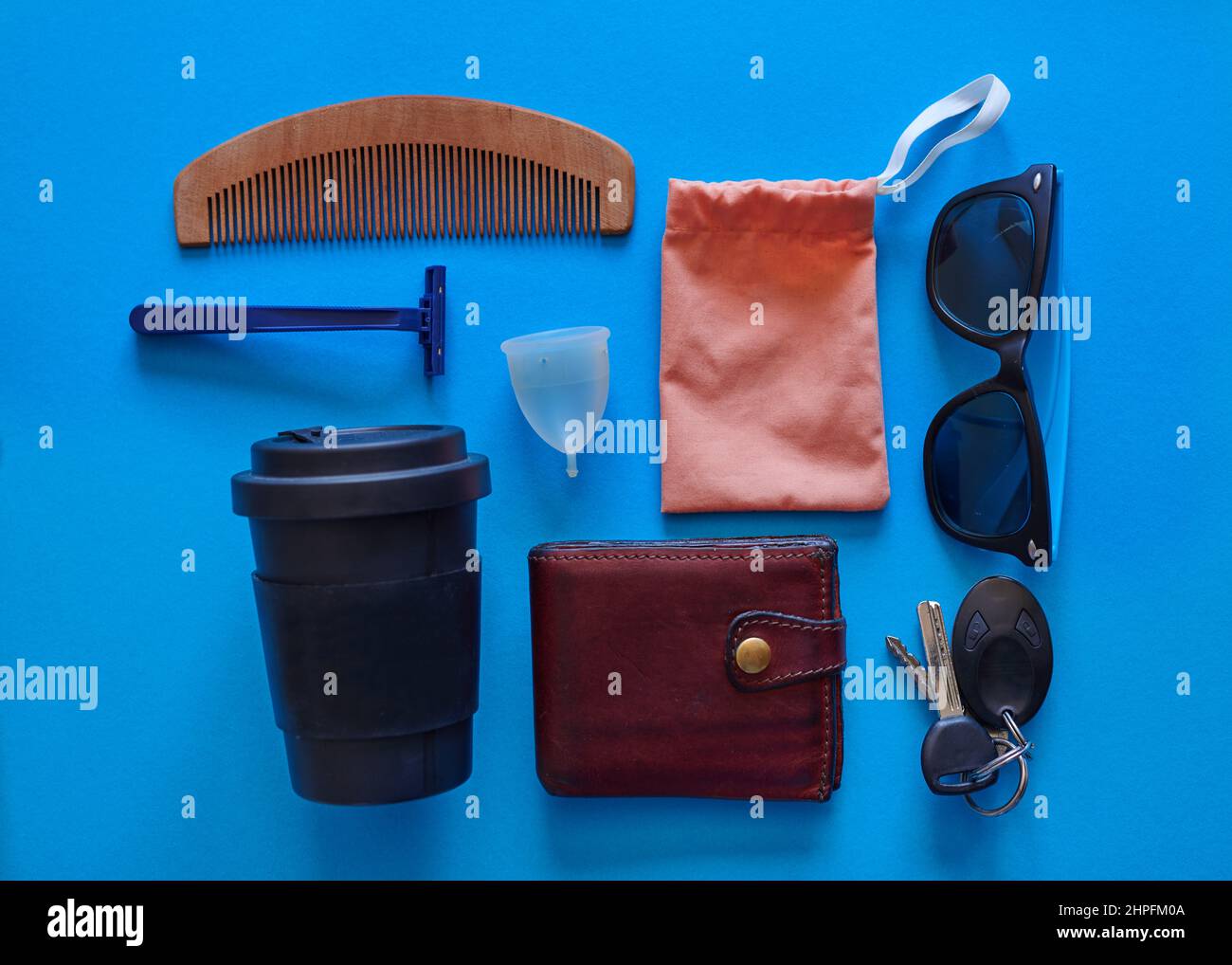 Una capa plana que muestra diversos objetos de estilo de vida de género con una taza menstrual Foto de stock