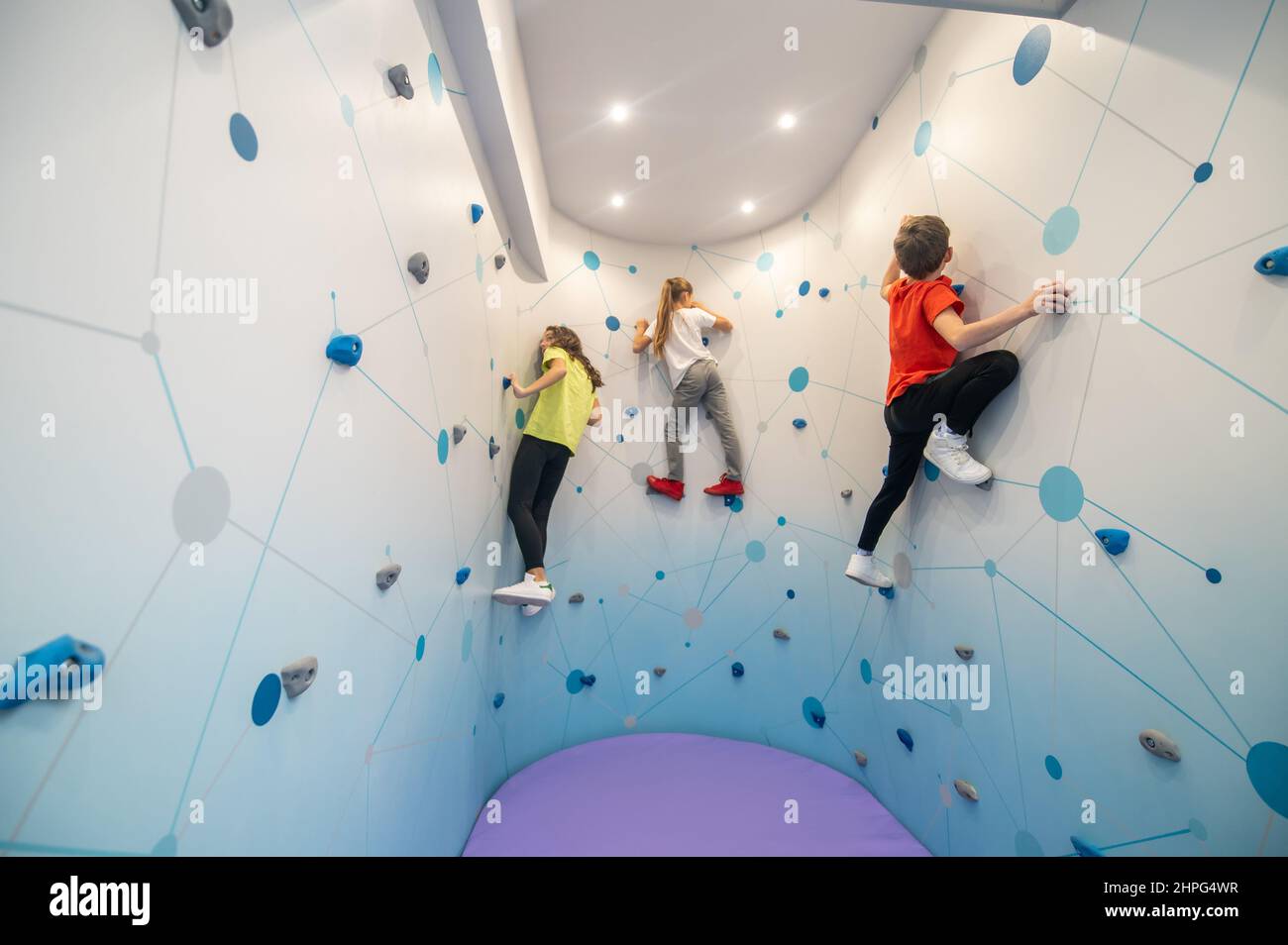 Niño y dos niñas pared de escalada en el interior Foto de stock