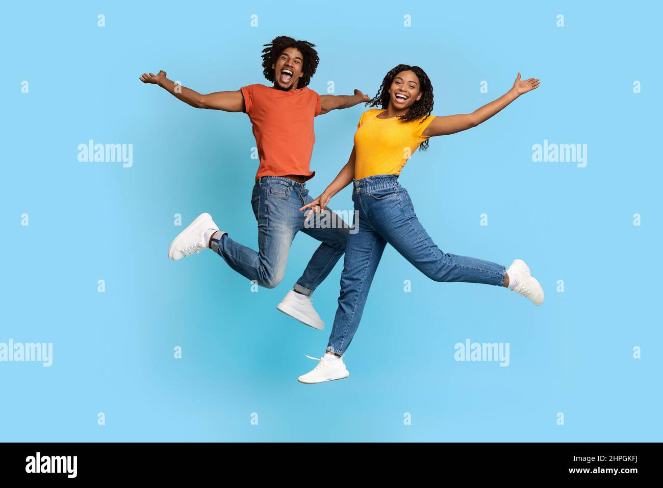 Alegre hombre y mujer afroamericana saltando sobre azul Foto de stock
