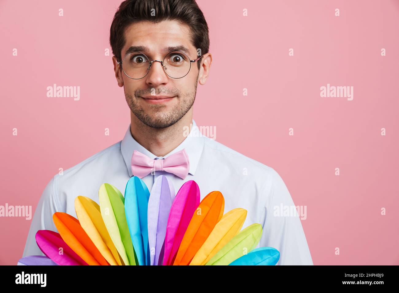 Joven sorprendido hombre usando lazo que posaba con ventilador multicolor  aislado sobre fondo rosa Fotografía de stock - Alamy