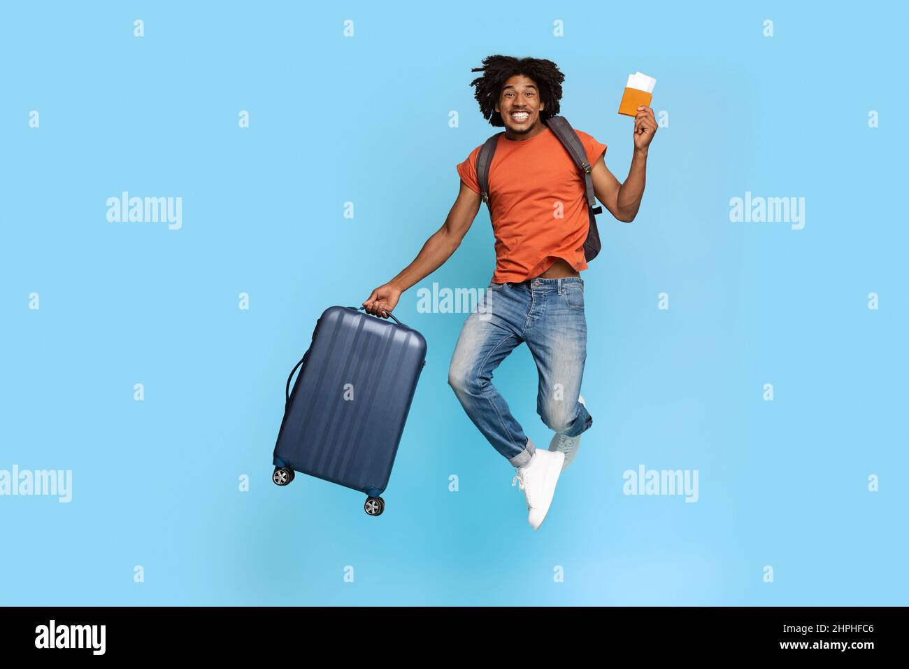 Emotivo afroamericano con maleta y billetes de avión saltando Fotografía de  stock - Alamy
