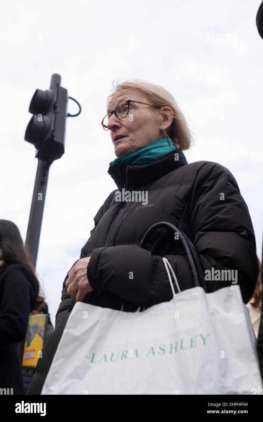 Mujer madura espera a cruzar la carretera con una bolsa Laura Ashley, Londres Reino Unido Foto de stock