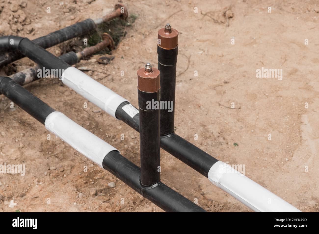 Reparación de la línea de agua de la tubería principal de calefacción en la tubería de la zanja de tierra en la industria del trabajo en el lugar de construcción. Foto de stock