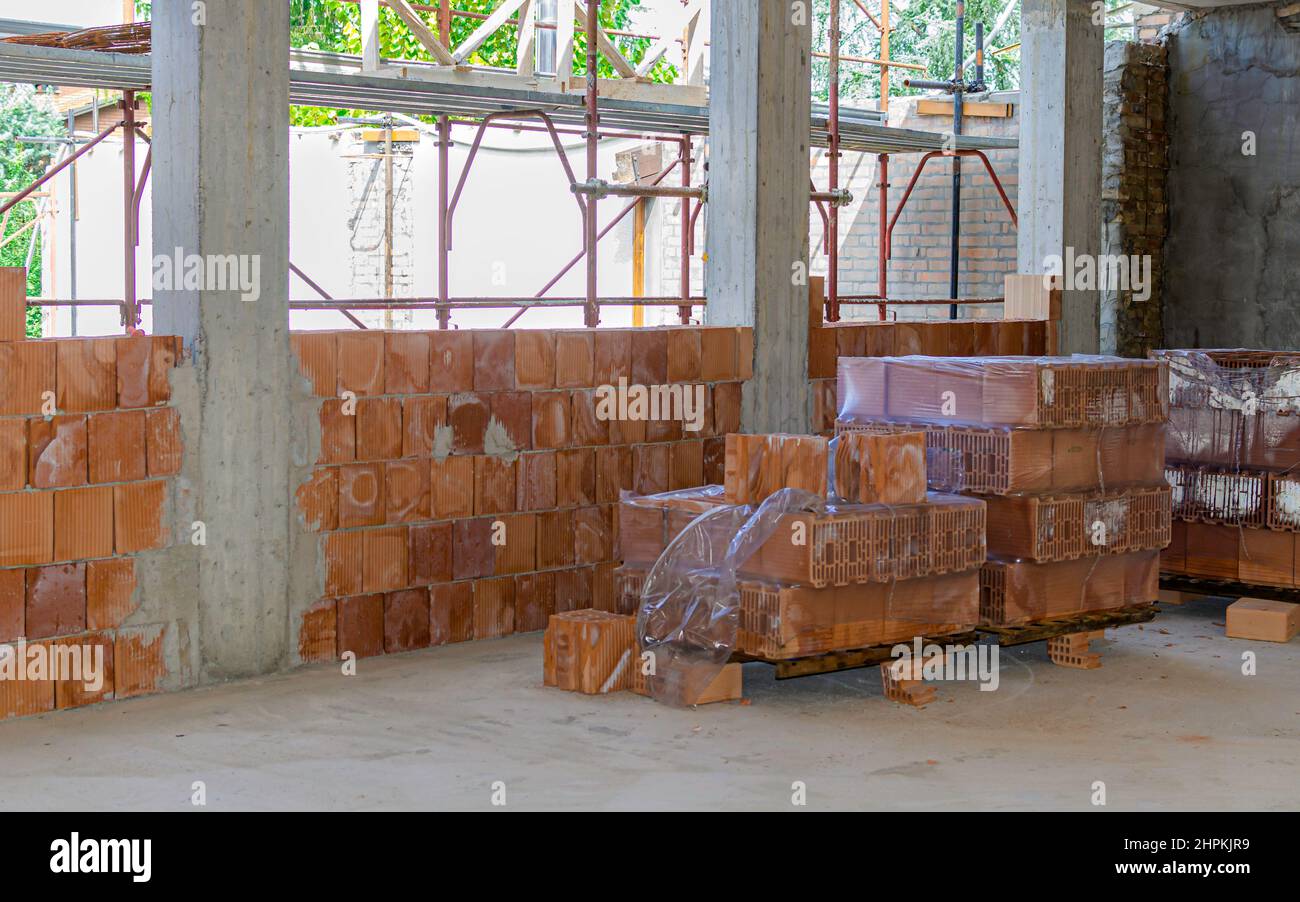 Pila de ladrillos, pala, escoba y otras herramientas de trabajo de una capa de ladrillos en un sitio de construcción Foto de stock