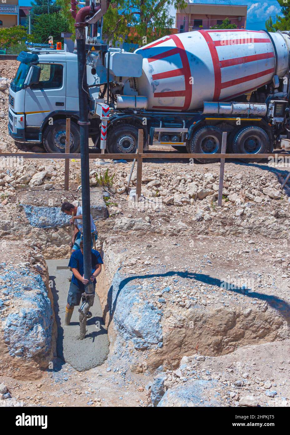 Trabajador de la construcción vertiendo hormigón, dirigiendo la bomba y trabajando en la fundación. Foto de stock