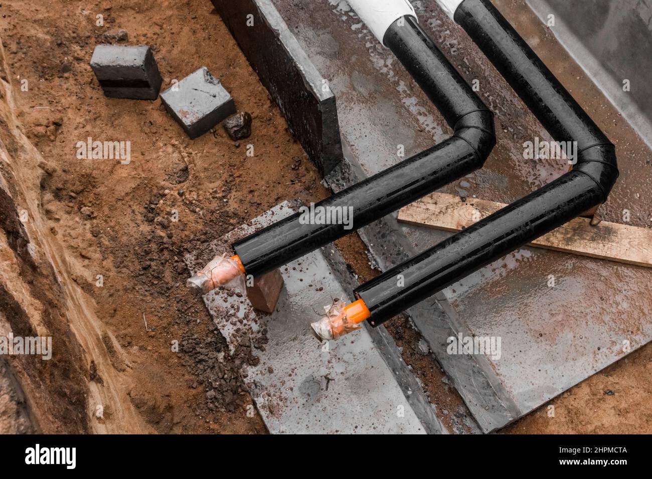 Reparación de la línea de agua de la tubería principal de calefacción en la tubería de la zanja de tierra en la industria del trabajo en el lugar de construcción. Foto de stock