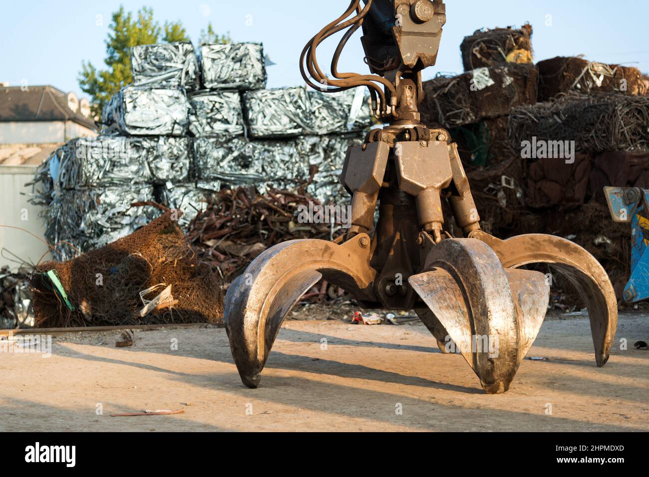 Excavadora de cadenas grande que trabaja una pila de acero en un patio de reciclaje de metal. Reciclaje industrial de chatarra - enfoque selectivo, espacio de copia Foto de stock
